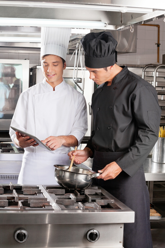 Szene in Hotelküche: Ein Koch am Topf, ein anderer mit iPad daneben